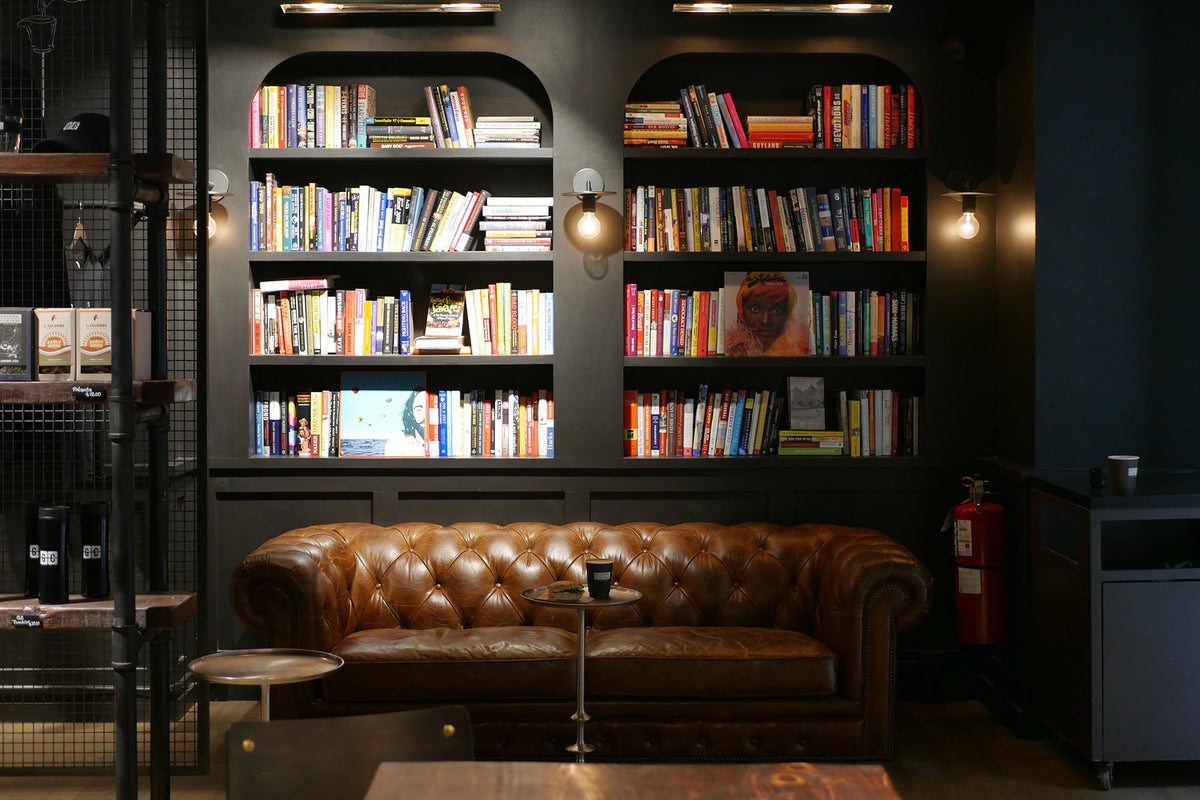 Leather chesterfield sofa beneath an arched bookshelf at GC Grand Central Station