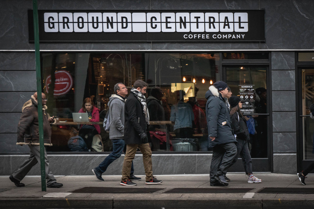 The GC Hell's Kitchen storefront on 8th Avenue with people passing on the sidewalk