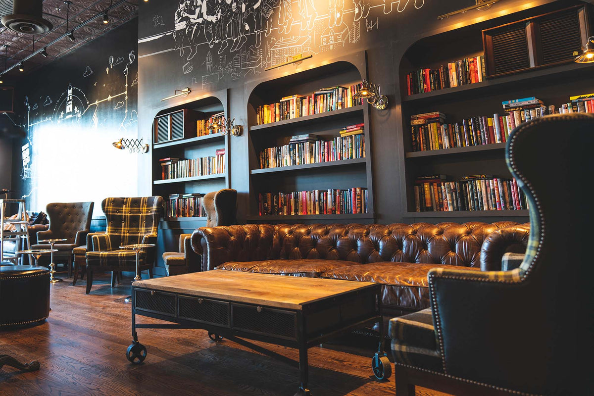 Lounge corner at GC Lynbrook with a leather sofa and floor-to-ceiling bookshelves