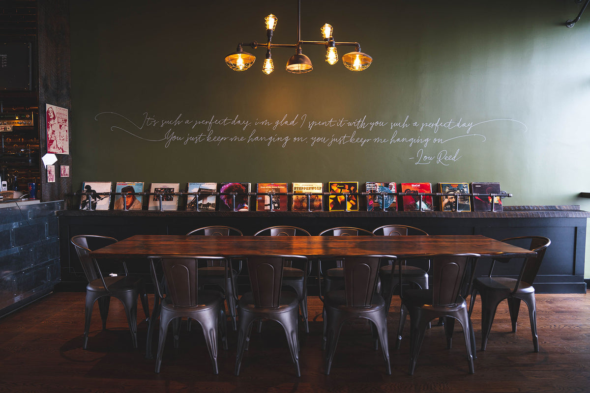 Long communal table under a brass chandelier at GC Lynbrook