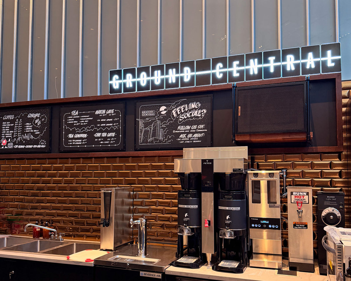 Brewing equipment below the Ground Central sign on the brick wall at GC Park Avenue Plaza
